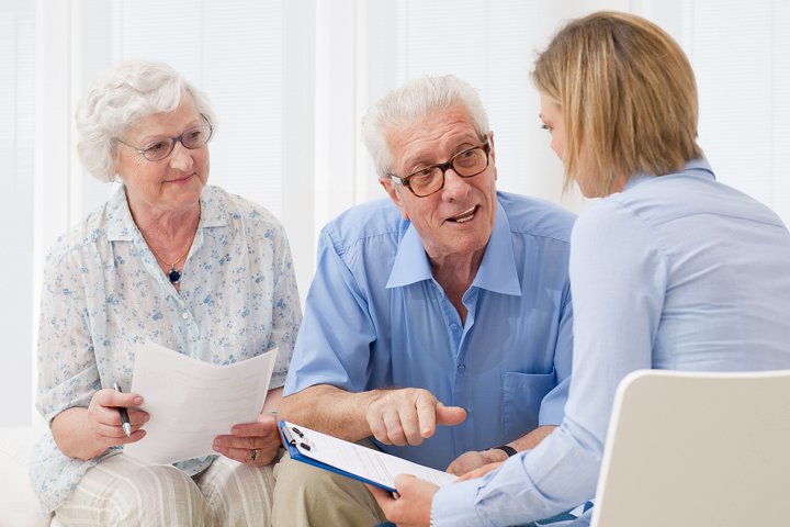 Elderly couple with advisor discussing ageing assistance.